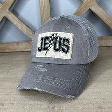 Load image into Gallery viewer, High ponytail trucker hat with the frayed rectangle patch that says, Jesus, in athletic print with a checkered lightening bolt in the milddle. 