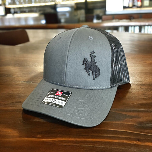 Richardson Lowpro 115 heather gray and black mesh trucker hat with an embroidered cowboy on bucking horse on front left side