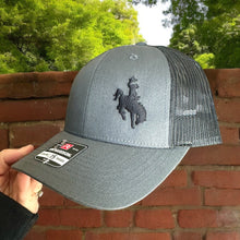 Load image into Gallery viewer, Richardson Lowpro 115 heather gray and black mesh trucker hat with an embroidered cowboy on bucking horse on front left side