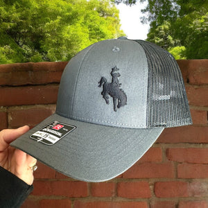 Richardson Lowpro 115 heather gray and black mesh trucker hat with an embroidered cowboy on bucking horse on front left side