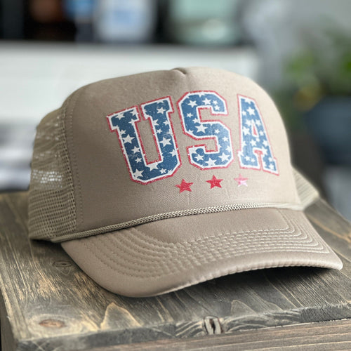 Tan trucker hat with USA printed on the front in a vintage red, white and blue.