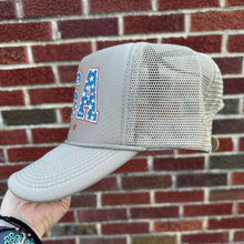 Load image into Gallery viewer, Tan trucker hat with USA printed on the front in a vintage red, white and blue.
