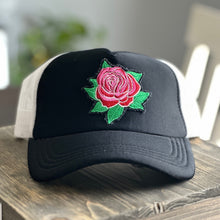 Load image into Gallery viewer, Black front and white mesh back mid profile trucker hat with an embroidered red and pink rose with green leaves patch. The patch has distressed edges.