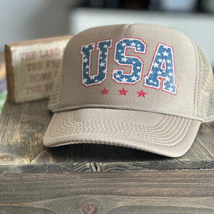 Tan trucker hat with USA printed on the front in a vintage red, white and blue.