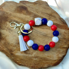 Load image into Gallery viewer, Red, white, and blue stretchy wristlet keychain with a white tassel and a gold keyring and lobster claw clip/