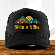 Load image into Gallery viewer, Black high profile foam trucker hat with a colorful mountain image with the words, Take a Hike in yellow retro font