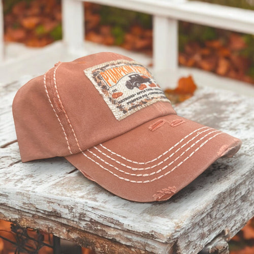 Dusty orange dad hat with white stitching and a light beige pumpkin patch patch with frayed edges and old time trucker.