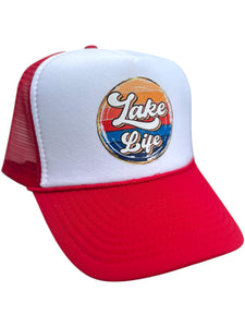 red/white high profile rope trucker hat with a colorful round Lake LIfe graphic printed on the front. Lake life is printed in white cursive bubble font. The colors in the background are in a strip pattern. Blues, yellows, reds