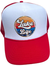 Load image into Gallery viewer, red/white high profile rope trucker hat with a colorful round Lake LIfe graphic printed on the front. Lake life is printed in white cursive bubble font. The colors in the background are in a strip pattern. Blues, yellows, reds
