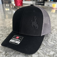 Load image into Gallery viewer, Black and charcoal mesh Richardson Low Pro 112 Trucker hat with an embroidered cowboy riding a bucking bronco. The thread is black making it tone on tone.