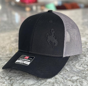 Black and charcoal mesh Richardson Low Pro 112 Trucker hat with an embroidered cowboy riding a bucking bronco. The thread is black making it tone on tone.