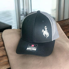 Load image into Gallery viewer, Beautiful gray embroidered cowboy Richardson Low Pro 115 Trucker hat - Black with gray mesh back. It&#39;s is sitting on a light brown sweatshirt.