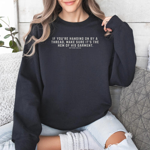 Black Gildan 18000 sweatshirt with the phrase, If you're handing on by a thread, make sure it's the hem of his garment. Matthew 9:20-22