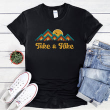 Load image into Gallery viewer, Black t-shirt with a vintage mountain sunset graphic that says, Take a Hike. Colors are yellow, turquoise, orange, and brown.