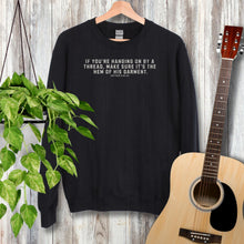 Load image into Gallery viewer, Black Gildan 18000 sweatshirt with the phrase, If you&#39;re handing on by a thread, make sure it&#39;s the hem of his garment. Matthew 9:20-22