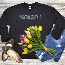 Load image into Gallery viewer, Black Gildan 18000 sweatshirt with the phrase, If you&#39;re handing on by a thread, make sure it&#39;s the hem of his garment. Matthew 9:20-22