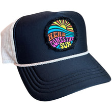 Load image into Gallery viewer, A black mid profile trucker hat with a cream rope and cream mesh. It has an embroidered here comes the sun round raggy patch. The image is embroidered onto a black frayed fabric using bright colors of orange pink, yellow, blue and teal.