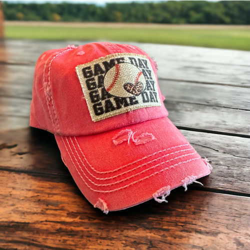 Vintage hot pink dad hat with a patch that says Game day four times with a baseball on top of the words with a small leopard print heart on the ball. The patch has frayed edges and the hat is distressed.