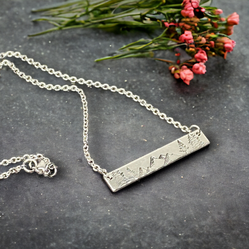 Silver hand stamped bar necklace with mountains and pine trees