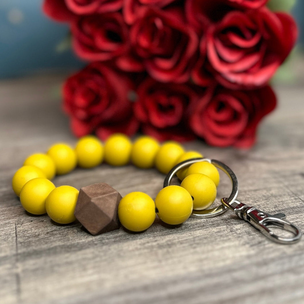 Gold This is a gold silicone wristlet keychain with a one handstained hexagon wood accent bead. The hardware is a flat 1.25 inch keyring with a silver claw clip. and Wood Wristlet Keychain