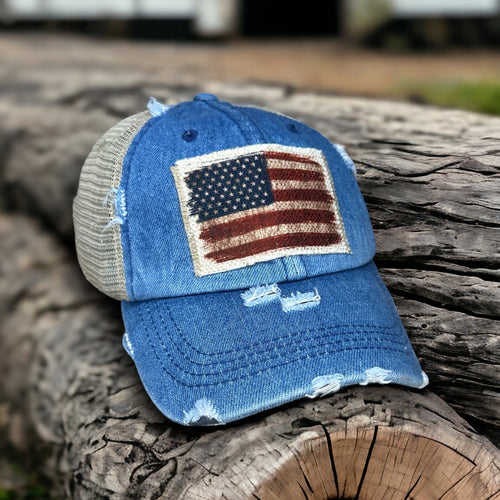 Denim blue high ponytail hat with tan mesh back. Velcro strap. Thehat is distressed and has a raggy edge patch with a.vintage American flag patch.