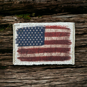Rustic American flag printed on tan polyester fabric that is frayed on the edges. It&#39;s a patch for a hat.