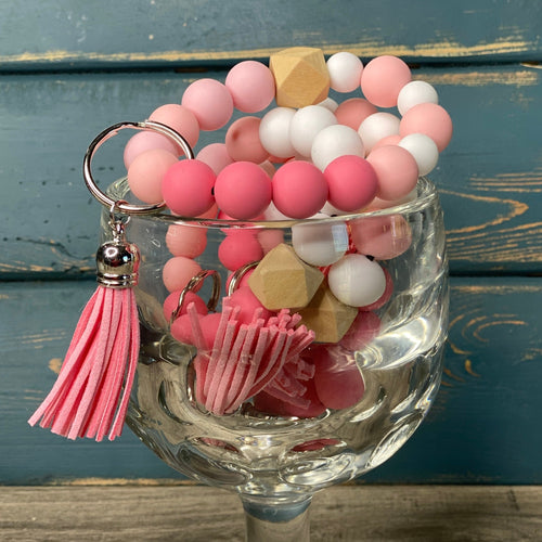 Dark pink, baby pink, and white silicone beads wristlet keychain with a light wood hexagon accent bead, pink tassel, and silver keyring